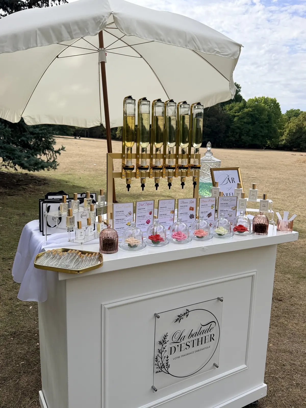 Le bar à parfums installé dans un parc sous une ombrelle crème